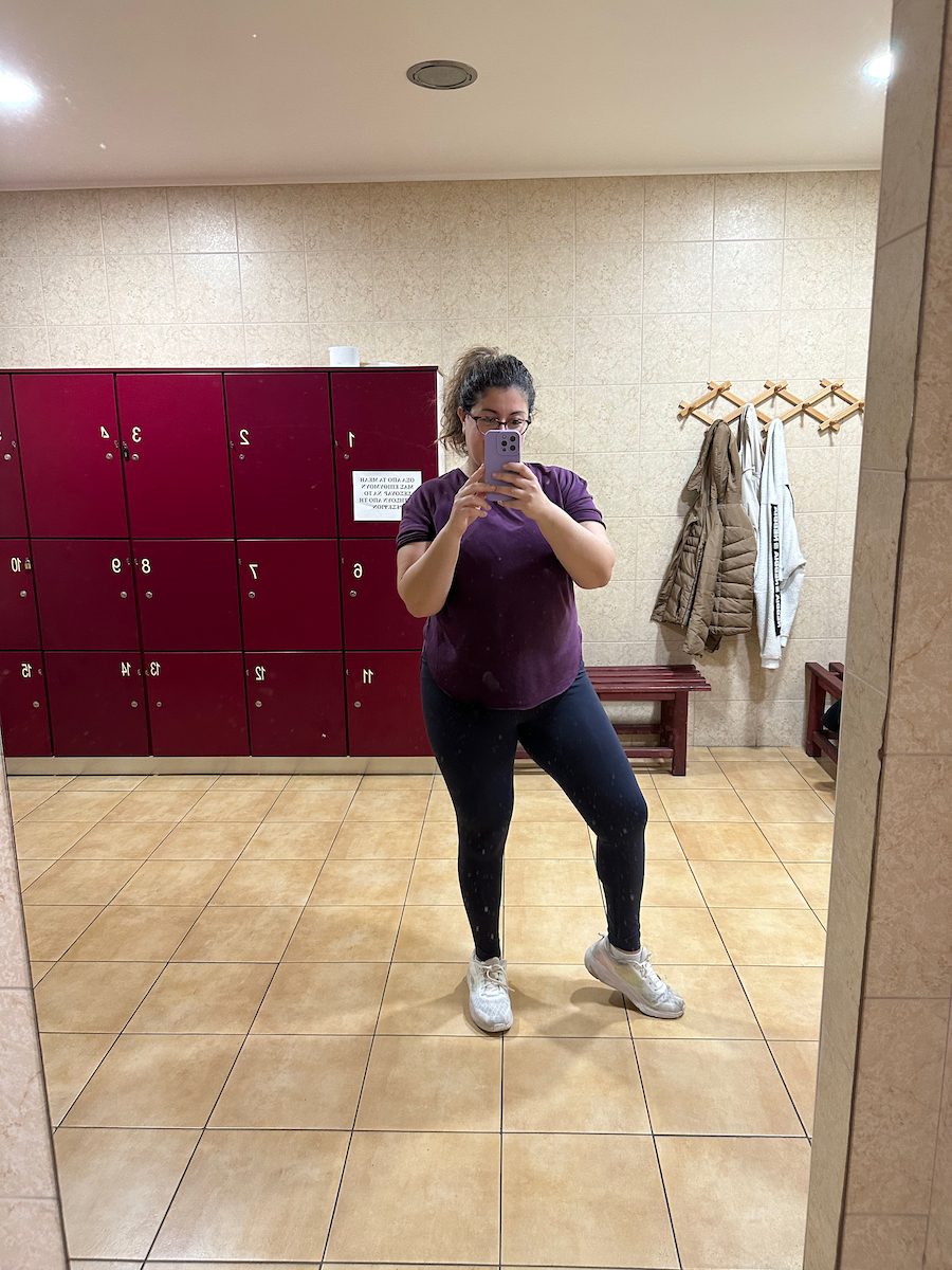 Girl in gym clothes and ponytail posing in front of a mirror