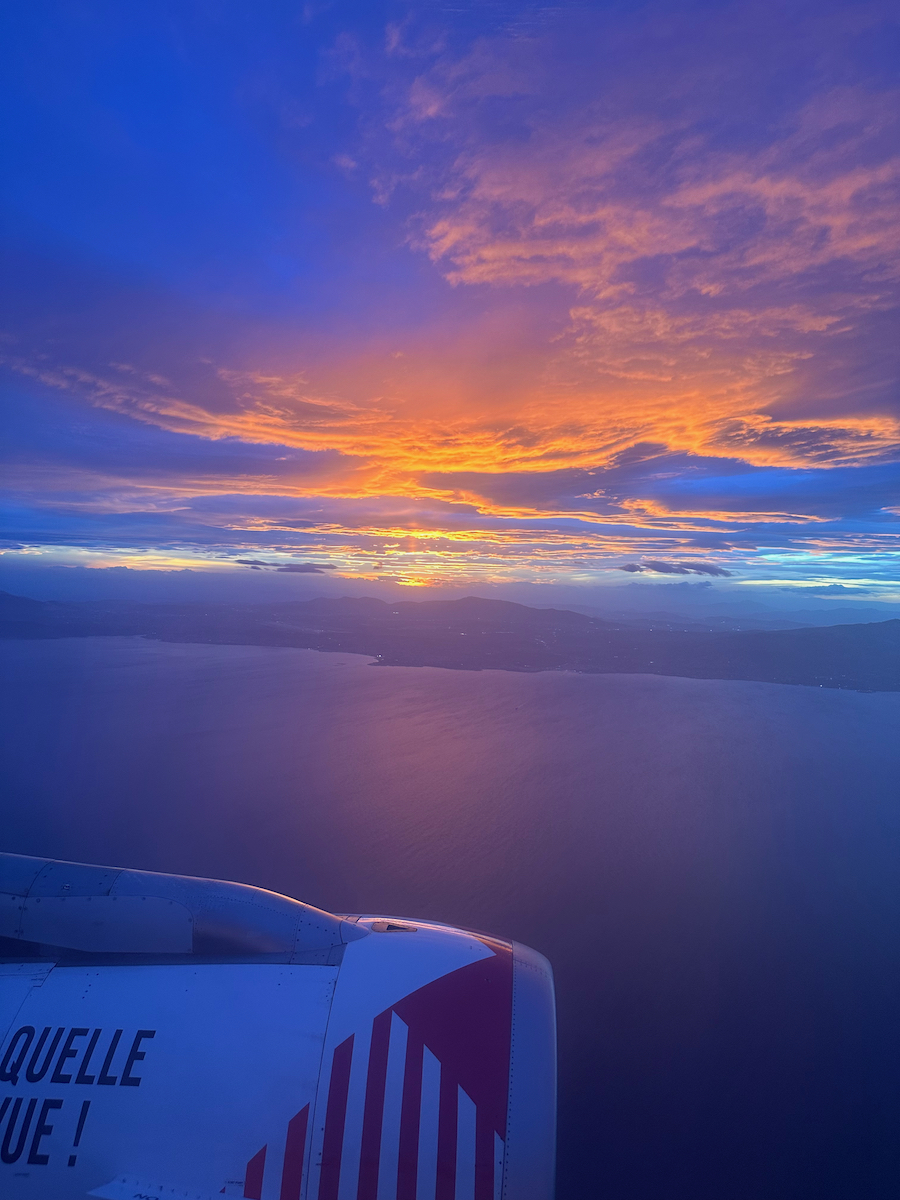 Colourful sunset view over Athens, plane wing visible on the bottom left